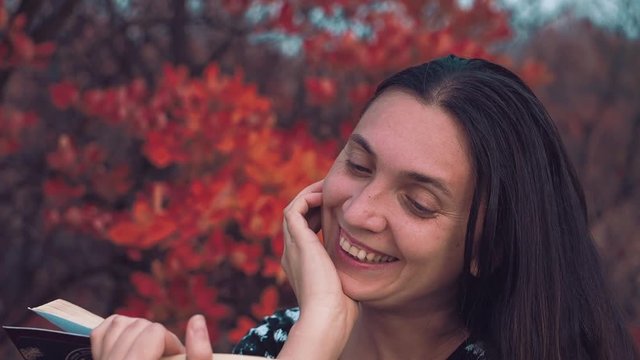The girl of European appearance conducts an orchestra of trees and leaves of the autumn forest Girl of the European appearance stands face to the autumn forest in the headphones and conducting the orc