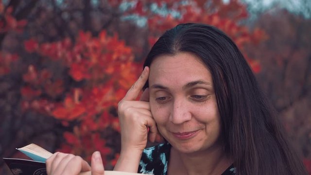 The girl of European appearance conducts an orchestra of trees and leaves of the autumn forest Girl of the European appearance stands face to the autumn forest in the headphones and conducting the orc