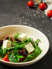 salad, leaves salad mix, tomato and cheese in a white plate (mix micro greens, juicy snack). food background - top view