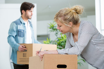 wife writing information on box for relocation