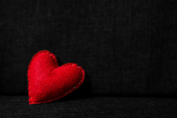 Obraz premium Red valentines day heart made from wool on dark fabric background. Concept of love 