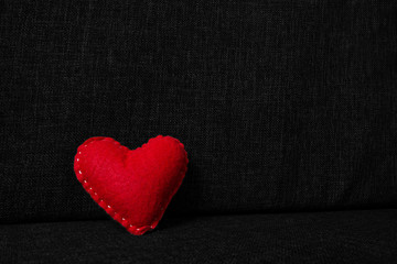 Red valentines day heart made from wool on dark fabric background. Concept of love 
