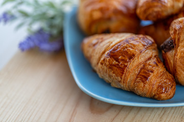 French croissants and buns with chocolate on a wooden table. Cooking and dessert. Bouquet of lavender flowers. Soft focus. Blurry background. Close-up. Macro. Copy space,