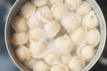 Saucepan with dumplings in hot water coming to a boil a second before filling the stomach semi-finished