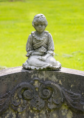 Fototapeta na wymiar Kleines Mädchen auf einem Grabstein