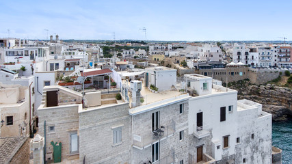 Fototapeta na wymiar Beautiful view of old town in Polignano a Mare in Italy. Houses and buildings built on cliffs next to ocean or sea. Luxury lifestyle at the edge of the world. Concept of travelling and summer holidays