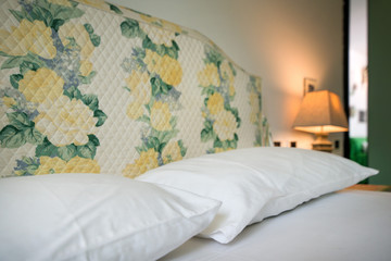 Lit up white bedroom lamps standing on wooden tables. Neutral colored modern bedroom with stylish...