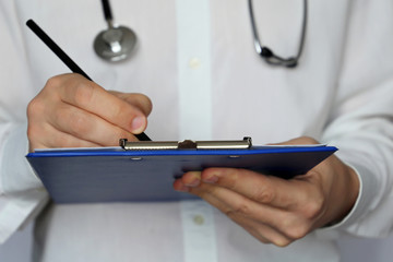 Doctor with stethoscope writes a prescription paper, medical exam. Concept of medicine, diagnosis, therapist, examination at the clinic, health care