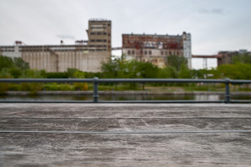 Wooden table old, against the background of the industrial building and the river