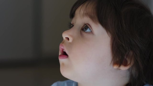 baby boy in blue t-shirt two years old watching TV at home