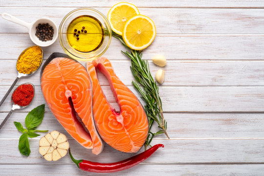 Two fresh Salmon steaks with seasonings and spices close-up on wooden white table. Diet and proper nutrition concept, top view and copy space.