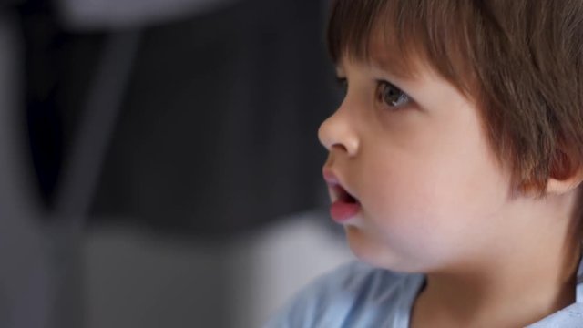 baby boy in blue t-shirt two years old watching TV at home