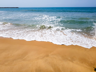 Soft waves from the ocean on a sandy beach. White seafoam on the beach.