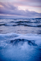 wave flushes on an icy beach colorful clouds in the background