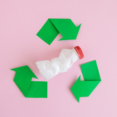 Flat lay of plastic bottle with recycling icon made of paper abstract on rose.