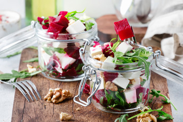 Beet salad with arugula, goat cheese and nuts, trendy salad jar, gray kitchen table background,...