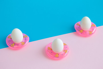 Three eggs in swimming pool floats abstract on colorful background.