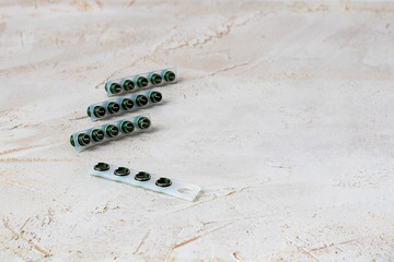 Many small wire thread inserts on plastic base, green and grey color, free running on grey cement background. Stainless Steel. Horizontal with copy space for text and design