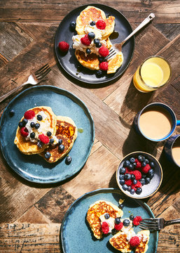 Overhead view of pancakes with fruit on wooden table
