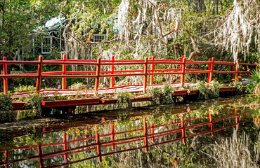 Water reflections of a red bridge in clear waters.