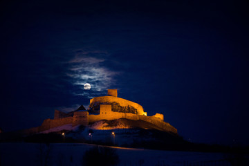 Dracula castle in the mountains in moonlight. Spooky palace in full moon, graveyard in front. Scary...