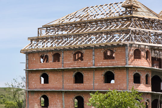 District for rich people with traditional, large gypsy house with luxury decorations and ornaments on the roof in Huedin, Romania. Houses being under construction. Concept of bankruptcy, and abandoned