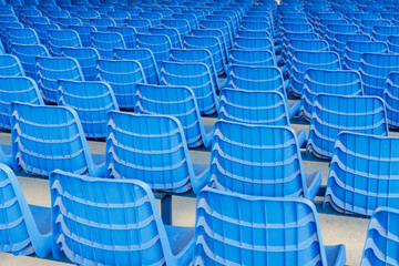 Rows of blue plastic chairs on a metal base. Back view