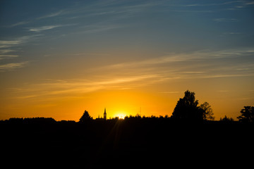 Silhouette of church and city on sunset or sunrise background. 