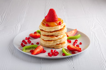 Stack of hot flapjacks served with fresh strawberries and kiwi