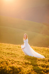 woman in a wedding dress runs across the field toward the mountains