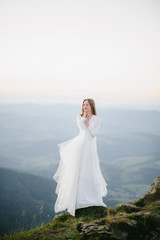 Fototapeta na wymiar woman in a wedding dress runs across the field toward the mountains