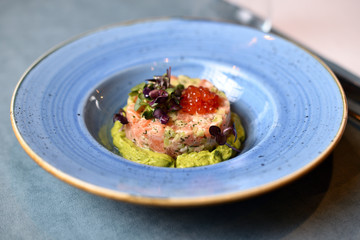 salmon tartare with red caviar on a blue plate