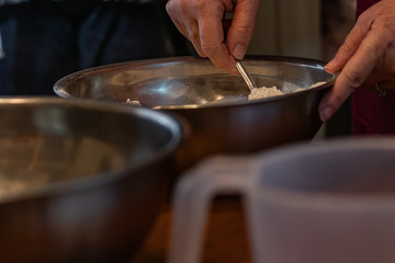 stirring fine white powder in a shiny metal bowl