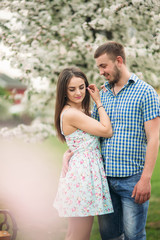 Young couple in love resting in the blooming garden. white blooming trees