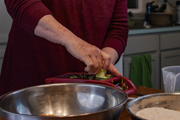 grandmother shredding zucchini with a cheese grater
