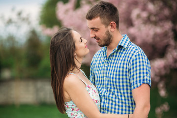 Obraz premium Young happy couple in love outdoors. Handsome man and beautiful woman on a walk in a spring blooming park. They keep helium balls
