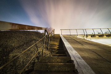 Stairs to the railway bridge at starry and cloudy night