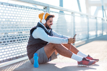 Male jogger resting and using phone,using social media