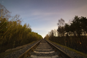 Railway track in the forest at cold starry night