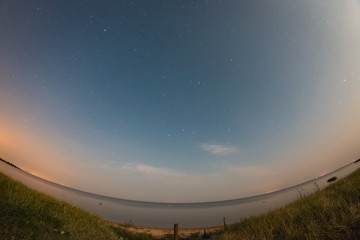 Starry night sky over the calm sea bay