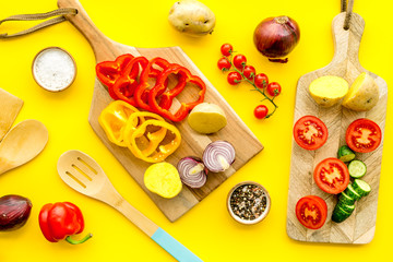 cooking with raw vegetables on yellow background top view