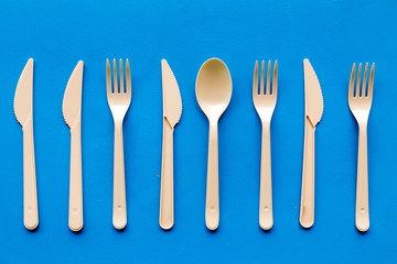 Plastic flatware for eco and Earth protection concept on blue background top view