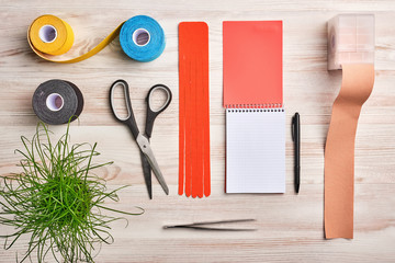 mock up with notebook, rolls of colored kinesio tape, scissors, tweezers and other tools