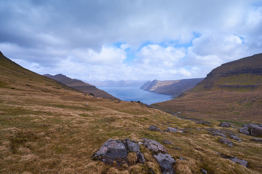 Scenic landscape Picture of large and deep fiord or fjord in Faroe island Eysturoy during cloudy morning in spring. Faroe islands in nord atlantic, part of Danish kingdom, pure scandinavian nature.