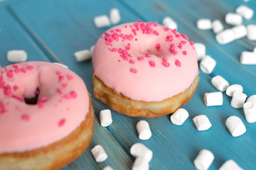 Photo with pink donuts and marshmallows on a blue wooden background. Sweets on a blue background. Pink donuts