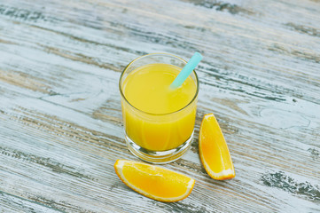 a glass of fresh orange juice with fresh citrus fruits on a light wooden table. horizontal view. citrus juice