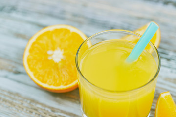 a glass of fresh orange juice with fresh citrus fruits on a light wooden table. horizontal view. citrus juice