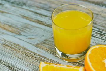 a glass of fresh orange juice with fresh citrus fruits on a light wooden table. horizontal view. citrus juice