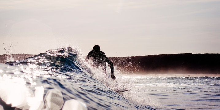 Silhouette of surfer on small wave