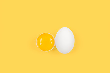 White egg and yolk.. Raw eggs on pastel yellow background.